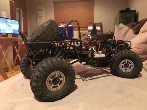 1989 Ford Bronco - A black remote control rock crawler with oversized tires and a roll cage is displayed indoors.