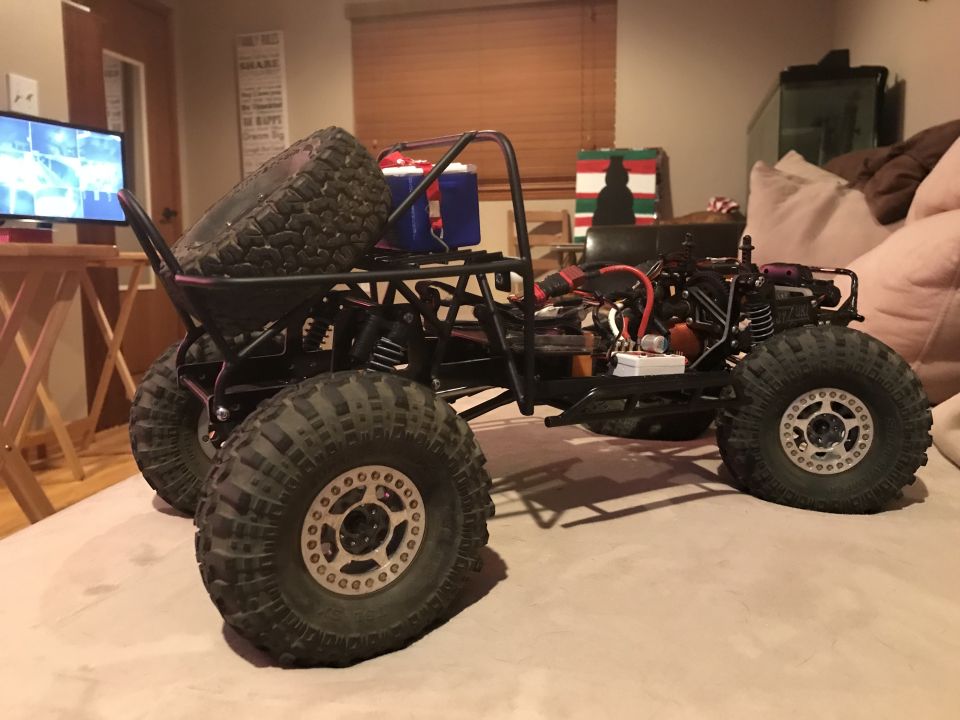 Black remote control rock crawler with large tires and a spare tire mounted on the back
