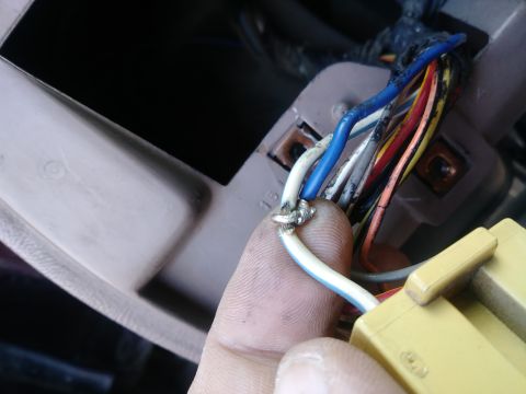 1996 Ford Bronco - A close-up view shows a person's finger holding a bundle of wires that have been spliced together with solder. The wires are connected to a…