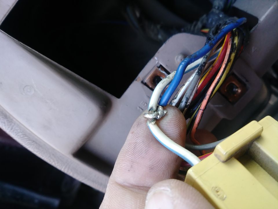 Close-up of spliced wires connected to a yellow electrical connector in a vehicle.