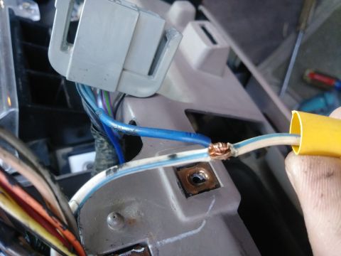 1996 Ford Bronco - A close-up view shows a person's hand holding a yellow wire loom over a spliced electrical connection between two wires. Several other wire…
