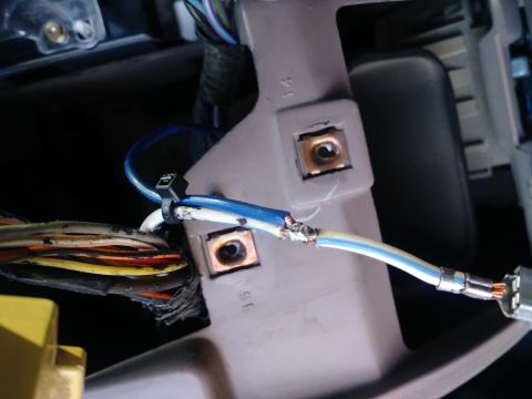 1996 Ford Bronco - Close-up view of spliced electrical wires, one blue and white, connected to a bundle of other wires. The wires are secured with a zip tie t…