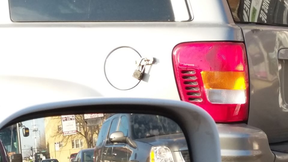 Silver vehicle with a padlock on its fuel door and a red taillight.