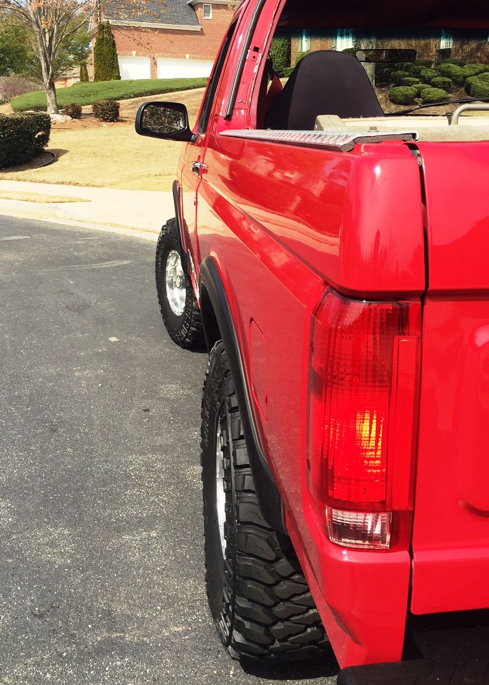 Red 1994 Ford Bronco rear passenger side view with off-road tires.