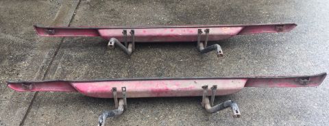 1994 Ford Bronco - Two red, weathered rear bumperettes with black metal brackets are displayed on a concrete surface. The bumperettes are identical and appear…