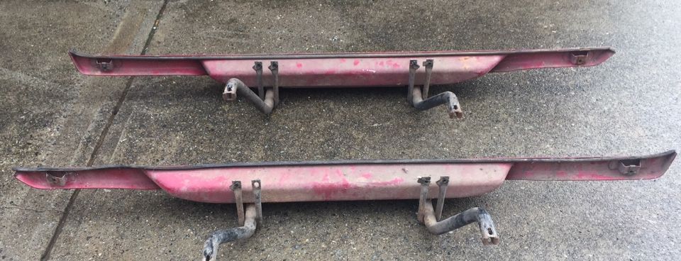 Two red bumperettes with black brackets on concrete