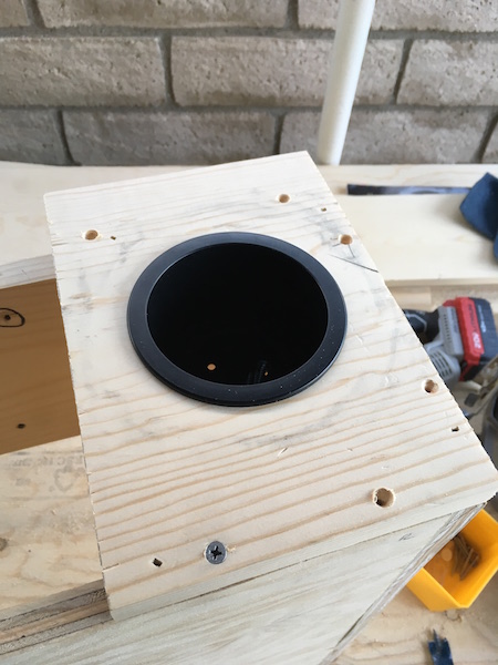1981 Ford Bronco - A close-up view of a wooden box with a circular black insert. The box is assembled with screws and has pre-drilled holes.