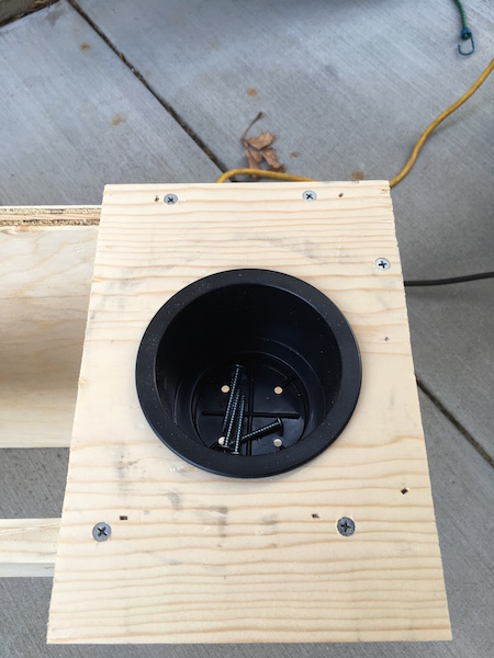 1981 Ford Bronco - A close-up view of a wooden structure with a black cup holder installed. Several screws are visible on the wood and inside the cup holder.