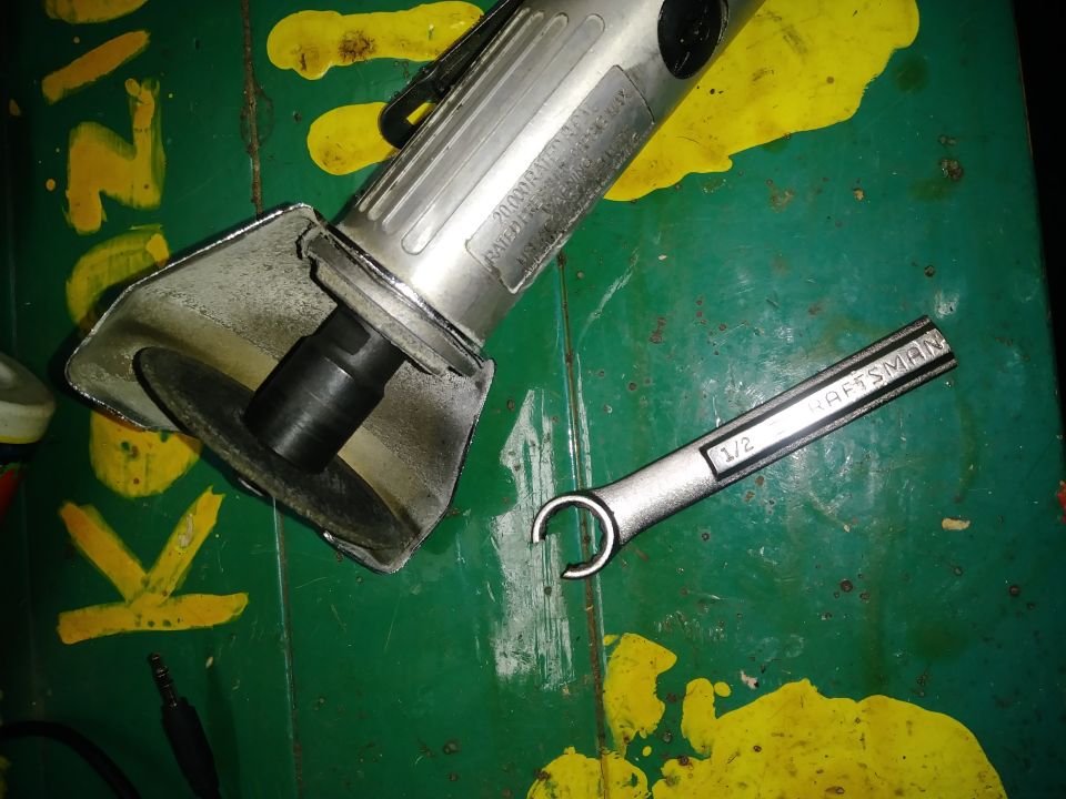Craftsman 1/2 inch wrench and angle grinder on a green surface.