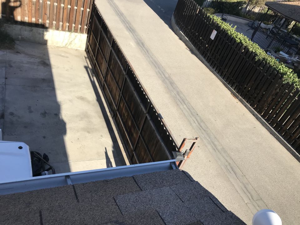 Rooftop view of a driveway and fence from a ladder