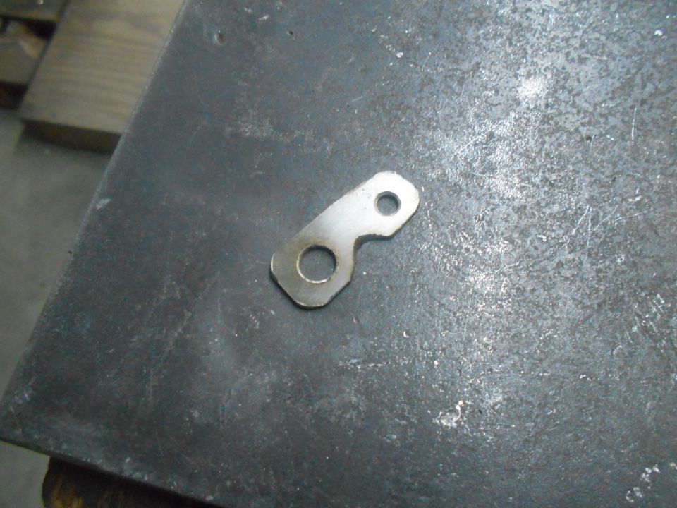 Metal bracket with two holes on a dark surface