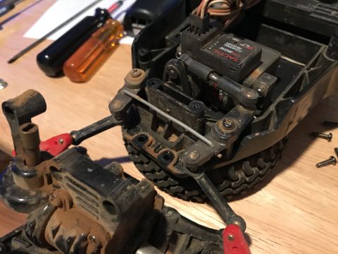 1989 Ford Bronco - A close-up view of the steering linkage and servo of a remote-controlled vehicle, likely undergoing maintenance or modification. Tools and…