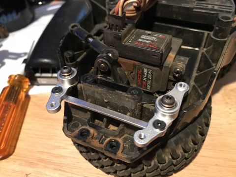 1989 Ford Bronco - A close-up view shows the steering servo and linkage assembly of an RC car, with a Tactic TSX45 metal gear servo visible. The linkage is ma…