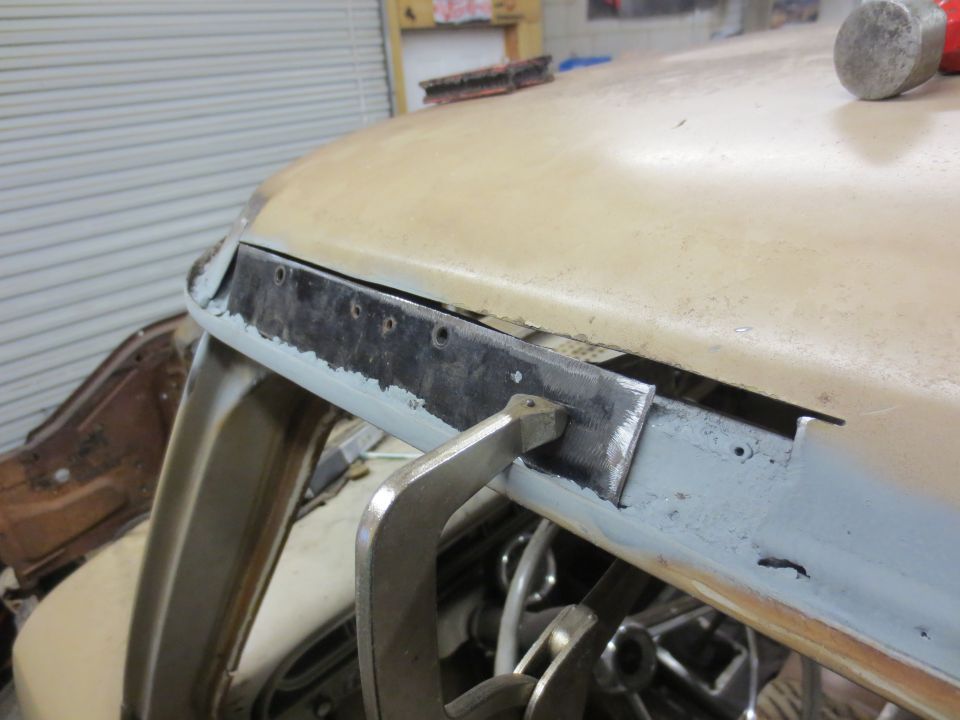 Close-up of vehicle windshield frame with metal trim and clamp during repair.