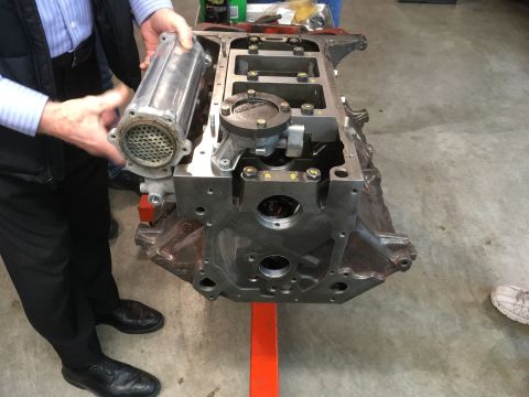 1968 Mercury Cougar - An engine block is shown on a stand, with a person holding a component near it.