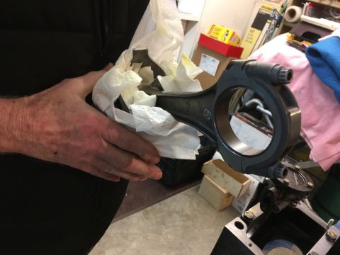 1968 Mercury Cougar - A close-up view of a single connecting rod, a crucial engine component, being handled with care.