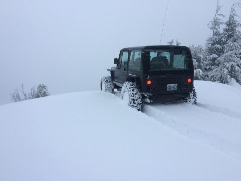 1995 Jeep YJ - A black 1995 Jeep YJ navigates a snowy trail, leaving tracks behind.