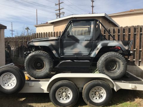 1987 Suzuki Samurai - A 1987 Suzuki Samurai with camouflage paint is parked on a trailer.