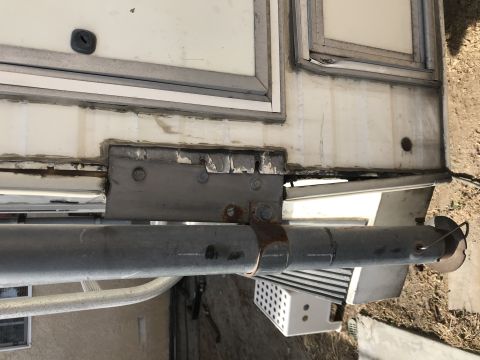 1997 Dodge 3500 - Detail view of a mounting bracket and roller assembly on the side of a camper.