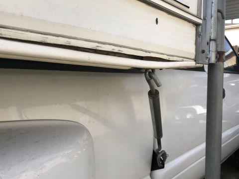 1997 Dodge 3500 - Detail of a camper shell attachment mechanism on a white pickup truck.