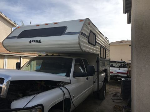1997 Dodge 3500 - A white 1997 Dodge 3500 pickup truck is fitted with a Lance camper shell, and its hood is open.