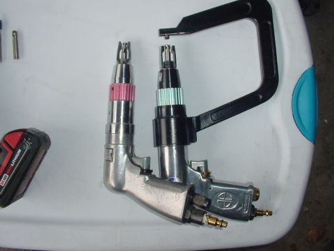 1967 Mercury Cougar - Close-up of two air-powered riveting tools and a battery pack on a white surface.