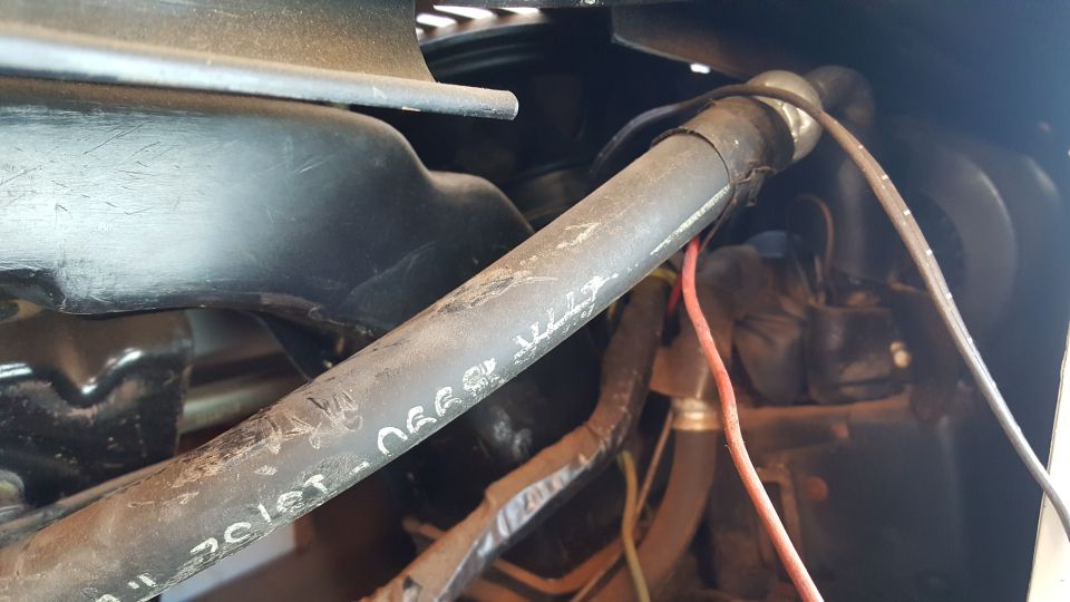 Close-up of engine bay hoses and wiring. White text is visible on a hose