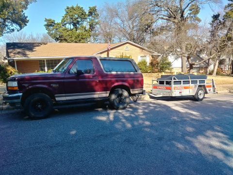1996 Ford Bronco - A Ford Bronco is hitched to a U-Haul trailer, parked on a residential street.