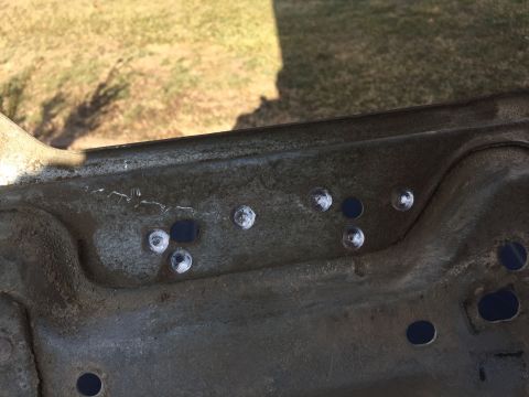 1996 Ford Bronco - Close-up view of a vehicle part, possibly from the engine bay, showing several bolts and circular openings.