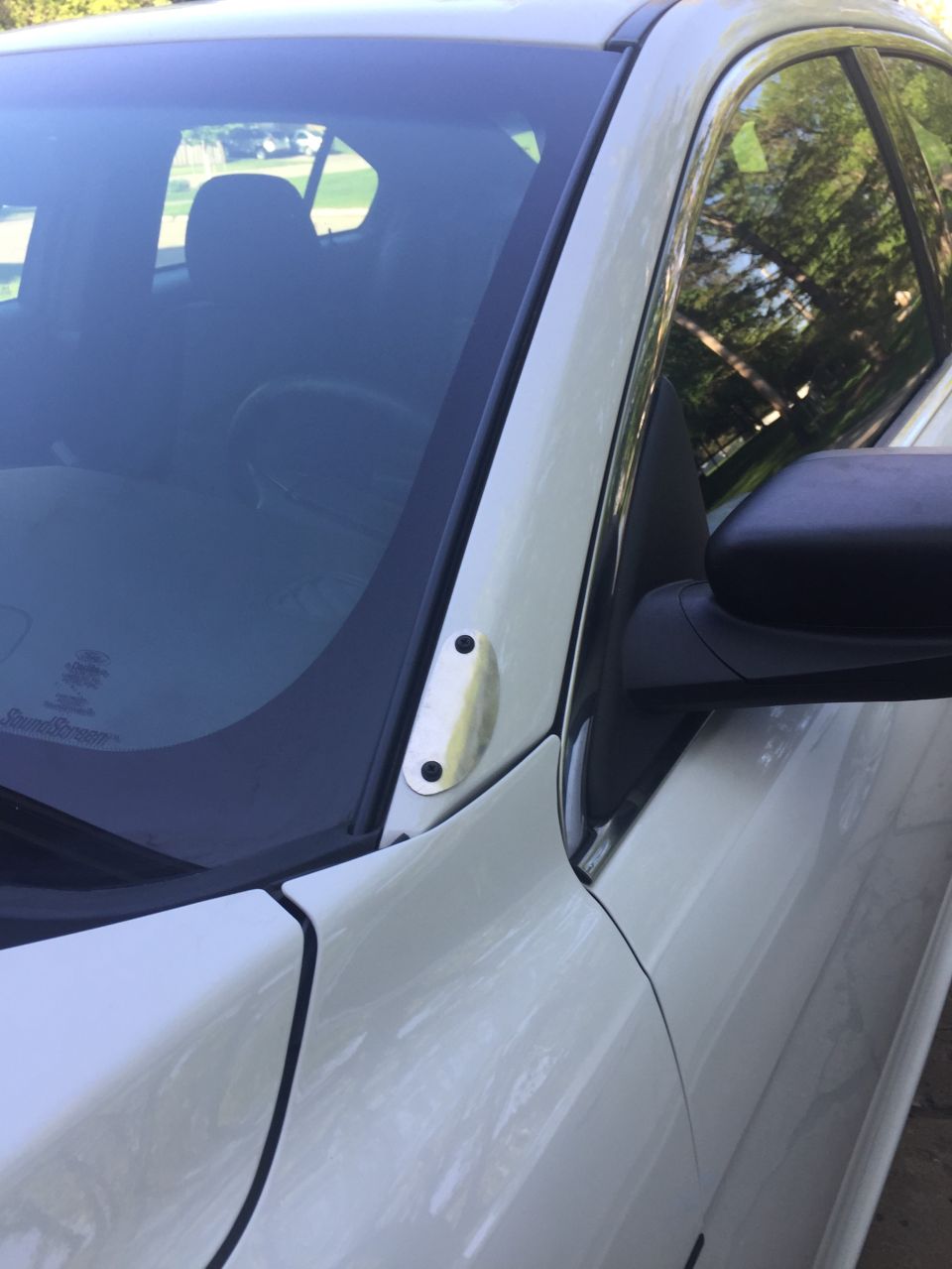 Close-up of a white car's A-pillar and side mirror mount