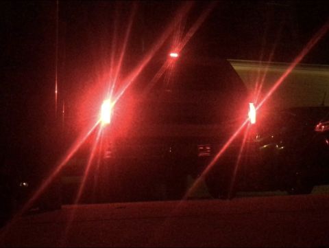 1995 Ford Bronco - Rear view of a dark SUV with illuminated red tail lights at night, alongside another vehicle.