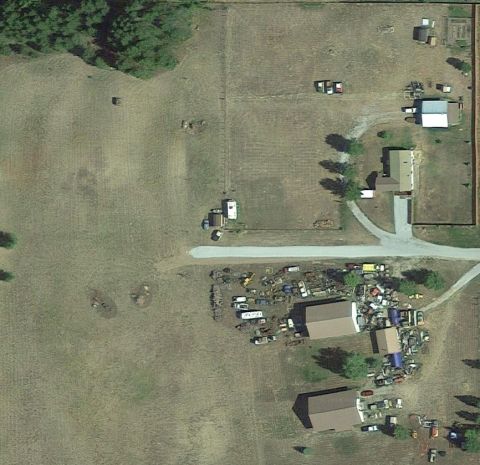 1995 Ford Bronco - An aerial view shows a rural property with numerous vehicles scattered around buildings and open fields.