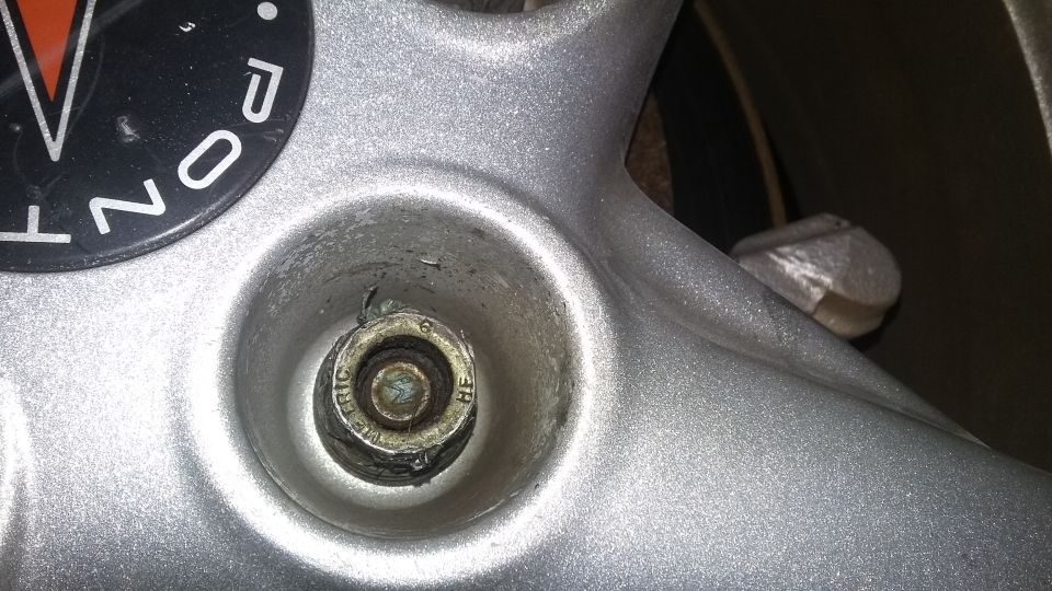 Close-up of wheel hub with Pontiac logo fragment and bolt