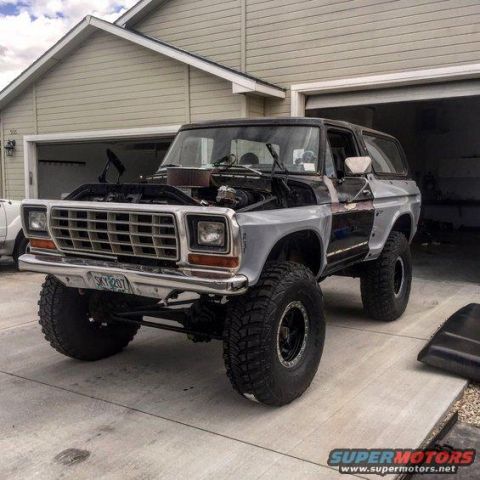 1979 Ford Bronco - A lifted 1979 Ford Bronco is parked in a driveway with its hood open, revealing the engine compartment.