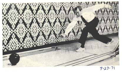 1967 Ford Custom Wagon - Man bowls in a bowling alley, with a diamond pattern on the wall and a bowling ball on the lane.