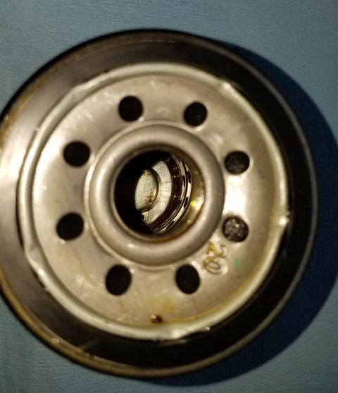 2000 Ford Crown Victoria - Oil filter base showing bolt holes and central threaded opening, with visible dirt and oil residue.