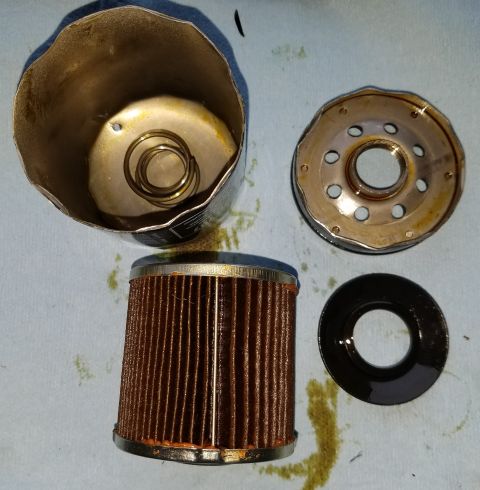 2000 Ford Crown Victoria - The components of an oil filter are laid out, showing the filter media, housing, and rubber seal.