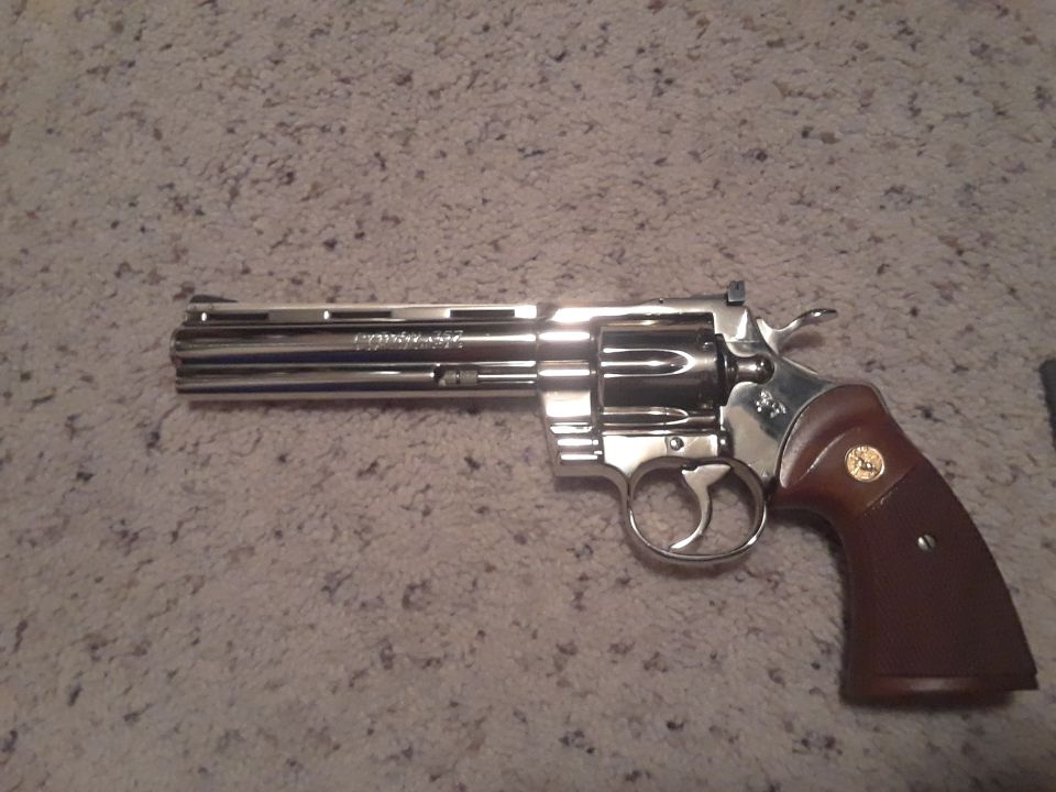 Chrome Colt Python revolver with wood grips on carpet