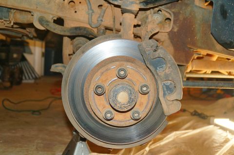 1998 Ford Ranger - Close-up of a vehicle's front brake rotor and caliper, supported by a jack stand.
