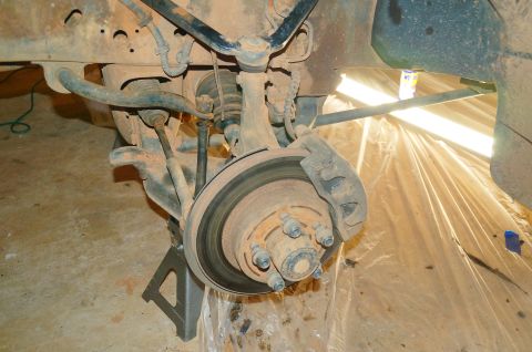 1998 Ford Ranger - Close-up of a vehicle's front suspension and brake system, supported by a jack stand.