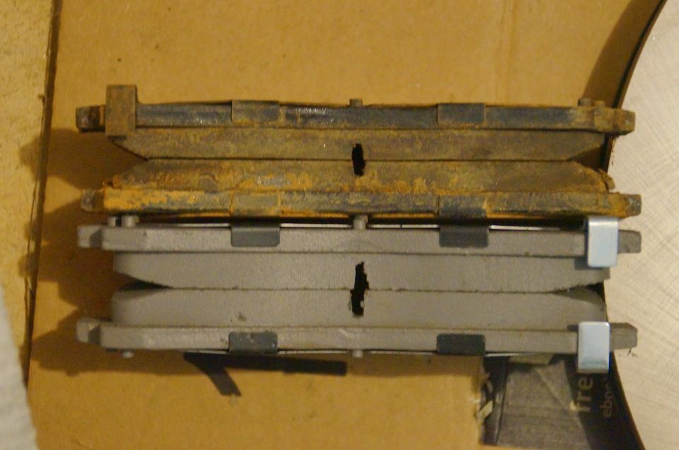Stack of old rusty brake pads on top of new brake pads