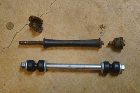1998 Ford Ranger - Comparison of a broken old stabilizer link and a new replacement part on a concrete floor.