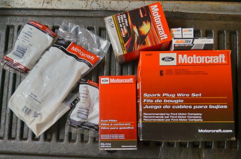 1998 Ford Ranger - A collection of Motorcraft engine parts, including a spark plug wire set, oil filter, and fuel filter, are laid out on a textured surface.