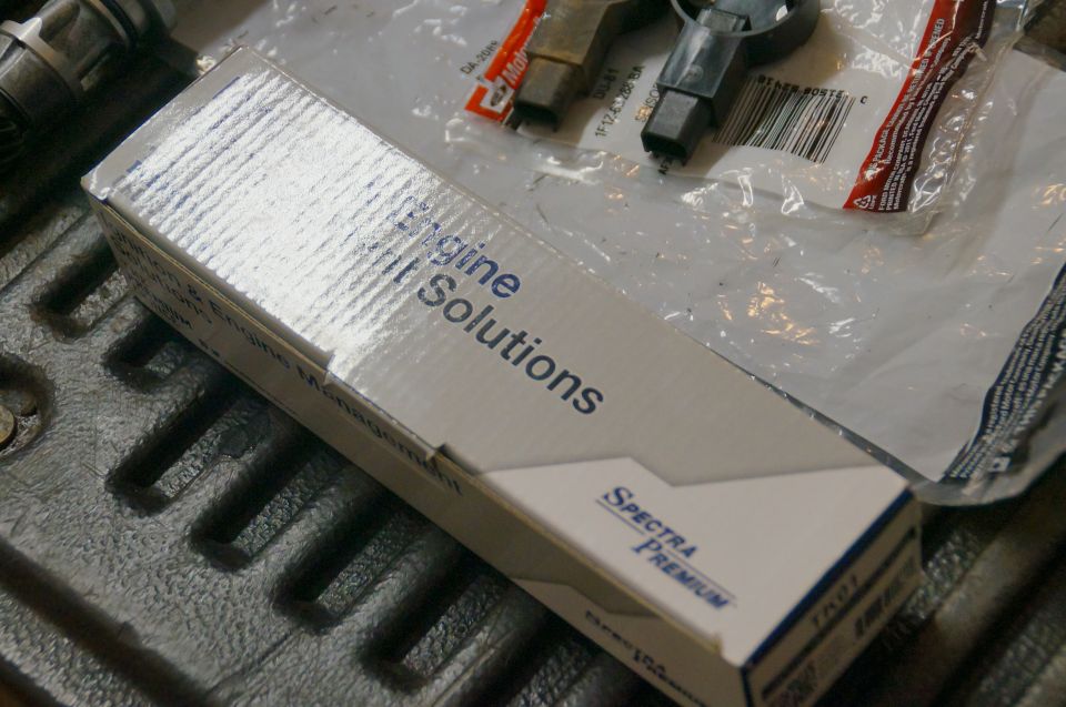 Spectra Premium engine management sensor in box with MotorCraft part beside it