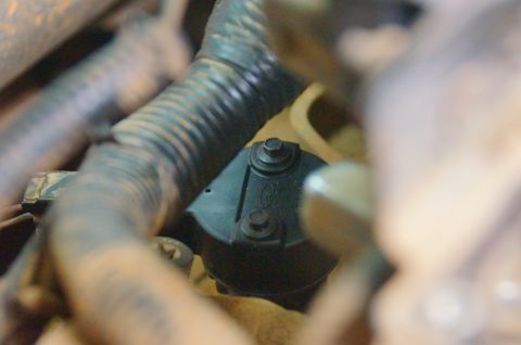 1998 Ford Ranger - A close-up view of a black Ford engine component, secured by two bolts, with the Ford logo visible.