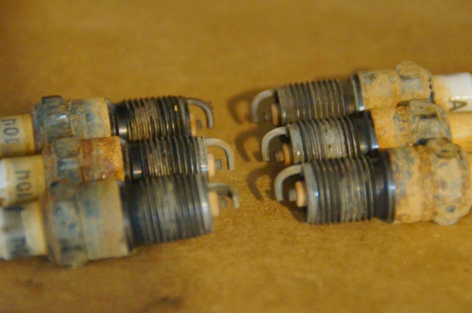 Six used spark plugs with visible wear and rust