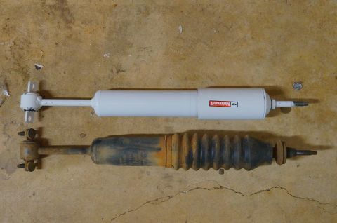 1998 Ford Ranger - A new Motorcraft shock absorber is shown next to an older, worn-out shock absorber with a protective rubber boot.