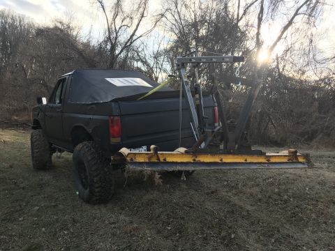 1989 Ford Bronco - This lifted pickup truck features a tow hitch attachment and a soft top cover over the bed.