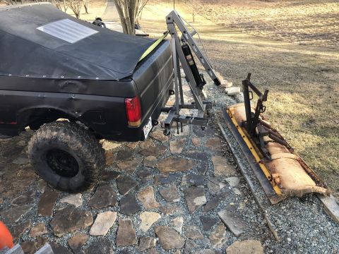 1989 Ford Bronco - Rear view of a black Ford Bronco with a tarp covering the bed and a dent on the driver's side rear quarter panel.