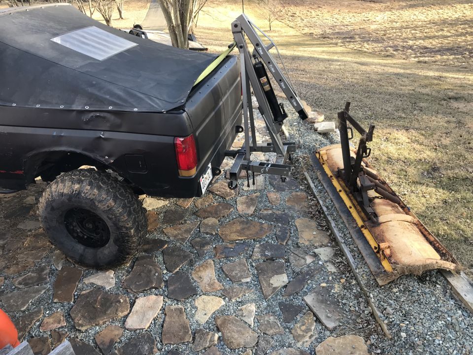 Black Ford Bronco with a tarp cover, large off-road tires, and a dent on the rear quarter panel
